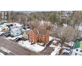 A red brick house with a brown roof in the middle of a snowy street.