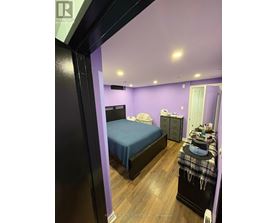 A bedroom with a bed, dresser, and nightstand.