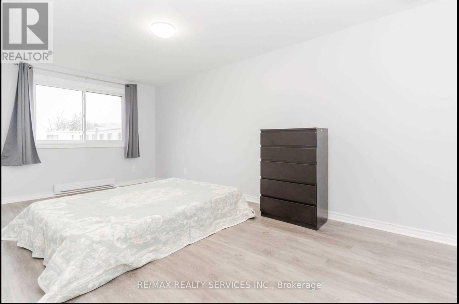 A bedroom with a bed, a dresser, and a window with curtains.
