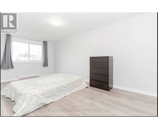 A bedroom with a bed, a dresser, and a window with curtains.