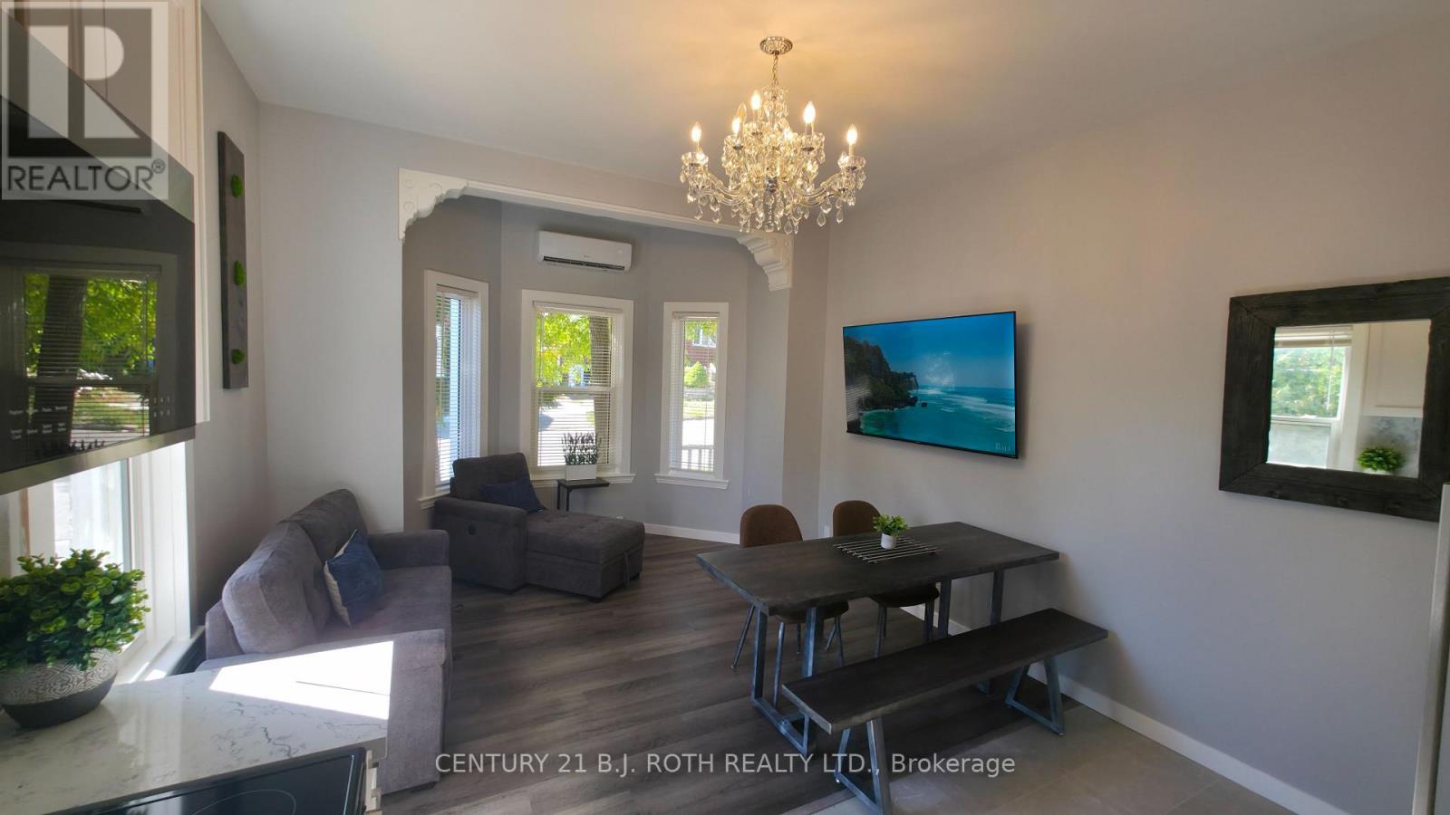 A living room with a grey couch, a black table, and a chandelier.