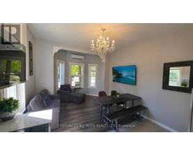 A living room with a grey couch, a black table, and a chandelier.