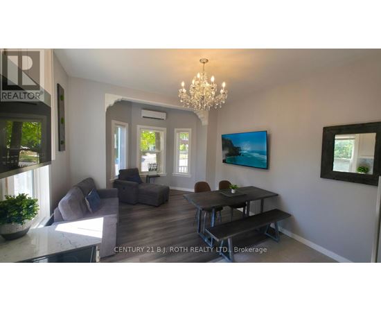 A living room with a grey couch, a black table, and a chandelier.