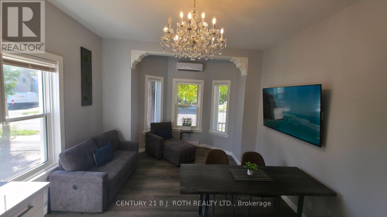 A living room with a grey couch and a chandelier.