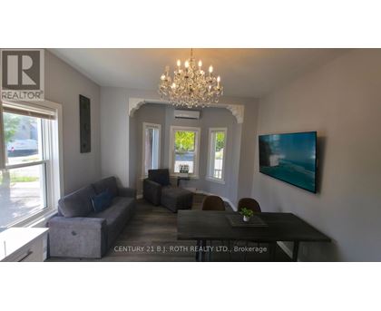 A living room with a grey couch and a chandelier.