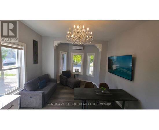 A living room with a grey couch and a chandelier.