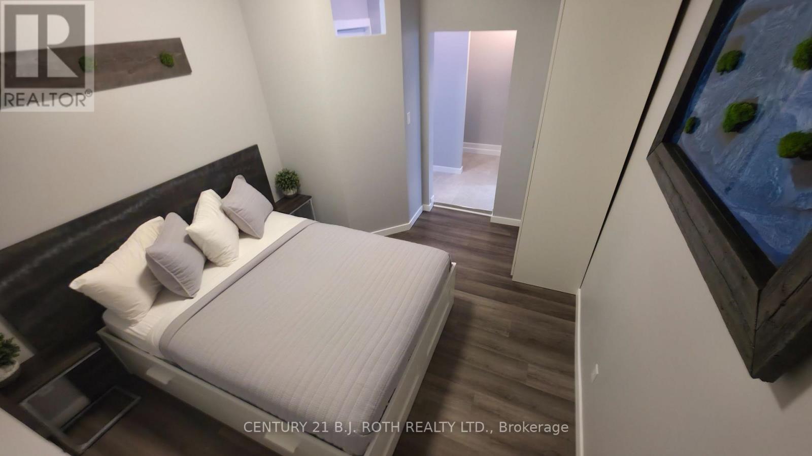 A bedroom with a bed, nightstand, and a painting on the wall.