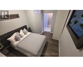 A bedroom with a bed, nightstand, and a painting on the wall.