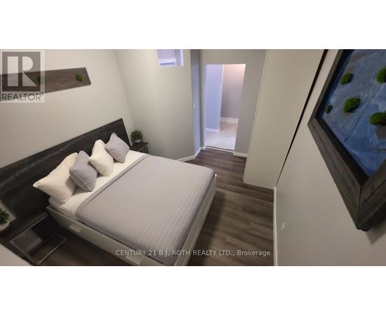 A bedroom with a bed, nightstand, and a painting on the wall.
