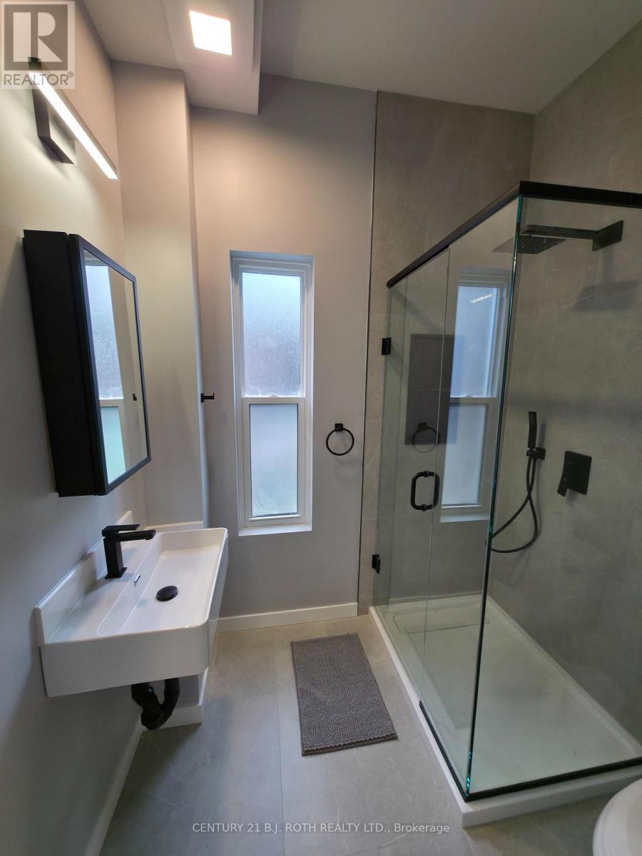 A bathroom with a sink, mirror, and shower.