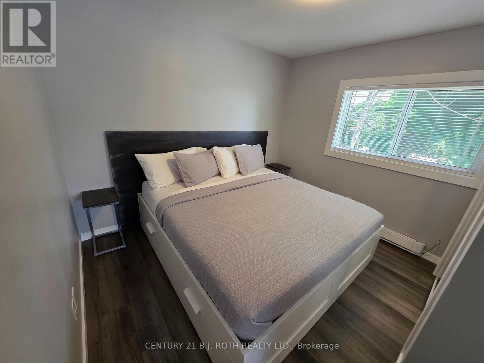 A bedroom with a bed, nightstand, and window.