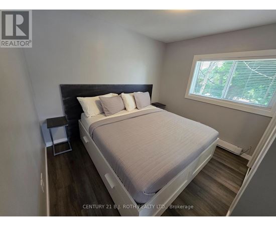A bedroom with a bed, nightstand, and window.