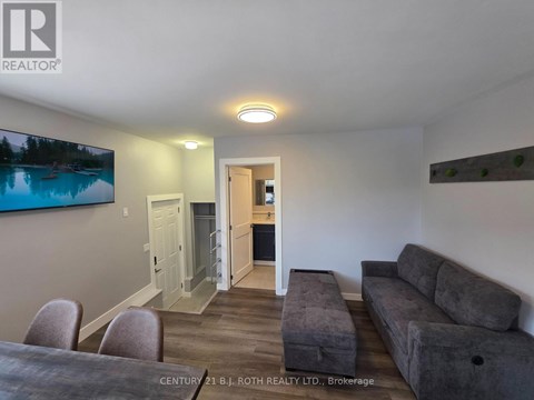 A living room with a grey couch and a television mounted on the wall.