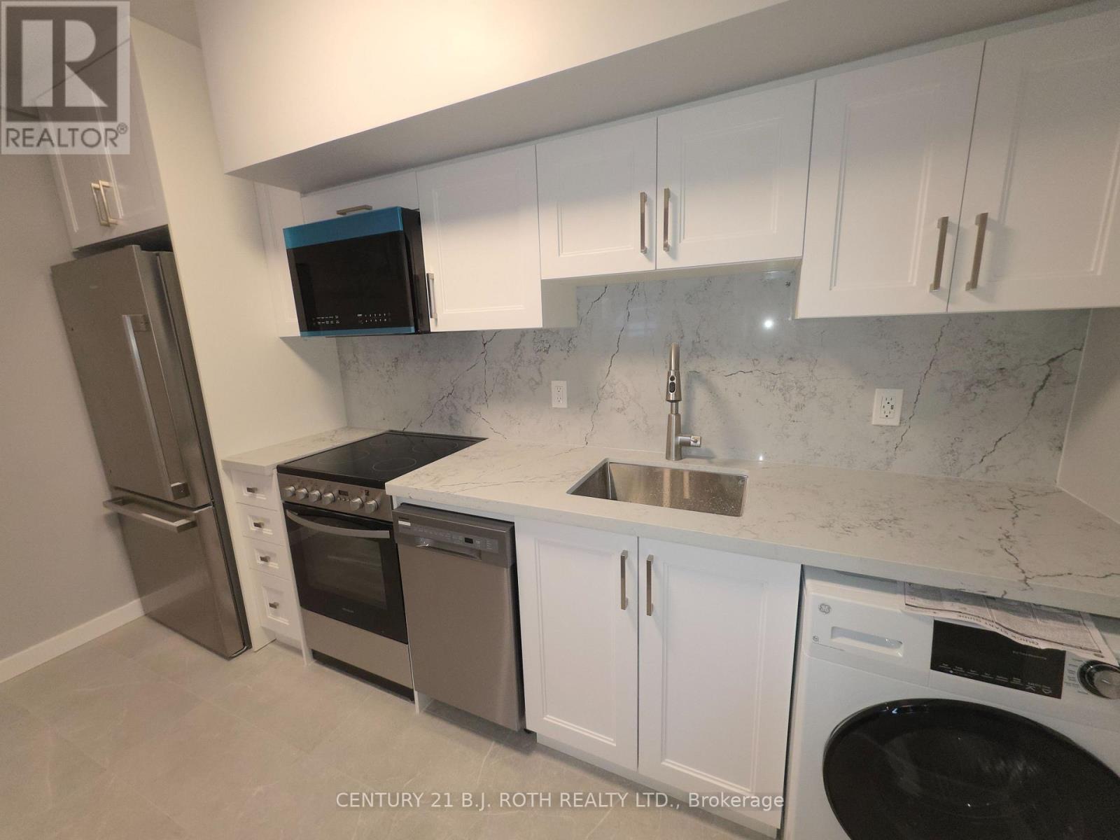 A kitchen with white cabinets and a marble countertop.