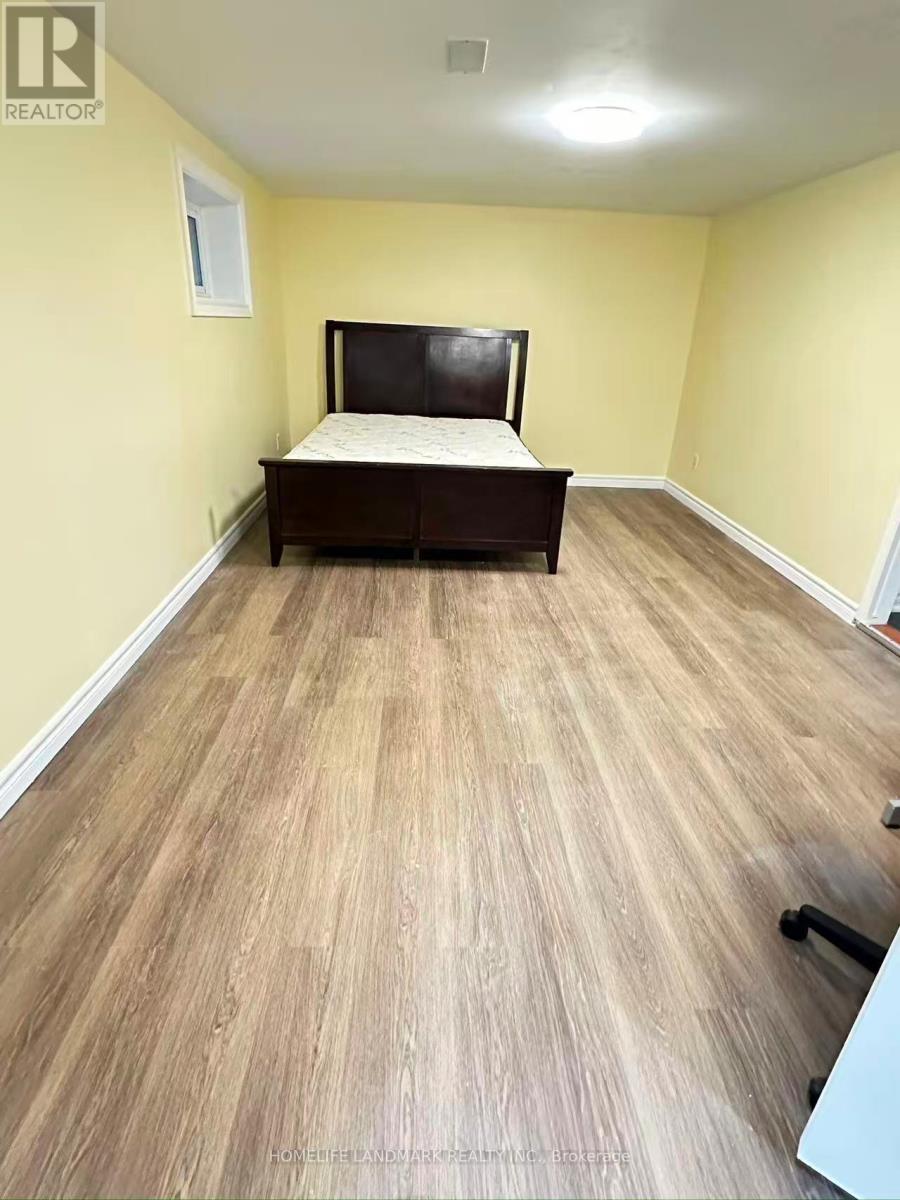 A bedroom with a bed, wooden flooring, and a window.