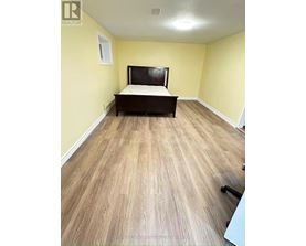 A bedroom with a bed, wooden flooring, and a window.