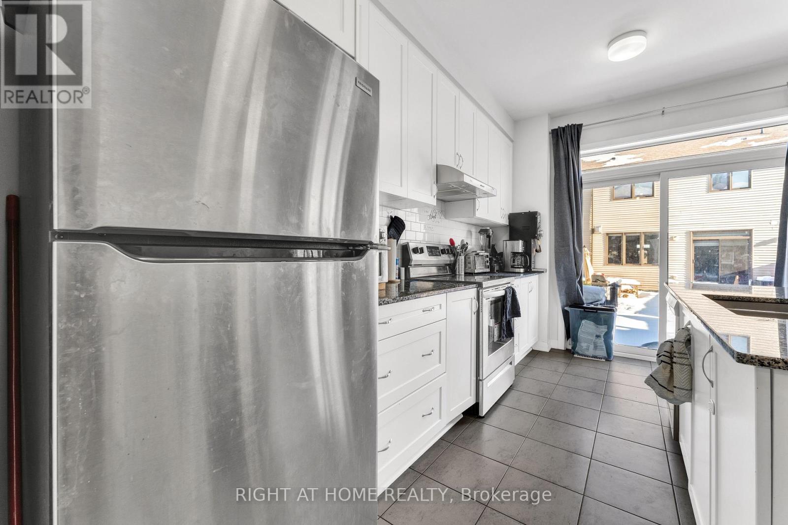 A modern kitchen with a stainless steel refrigerator and white cabinets.