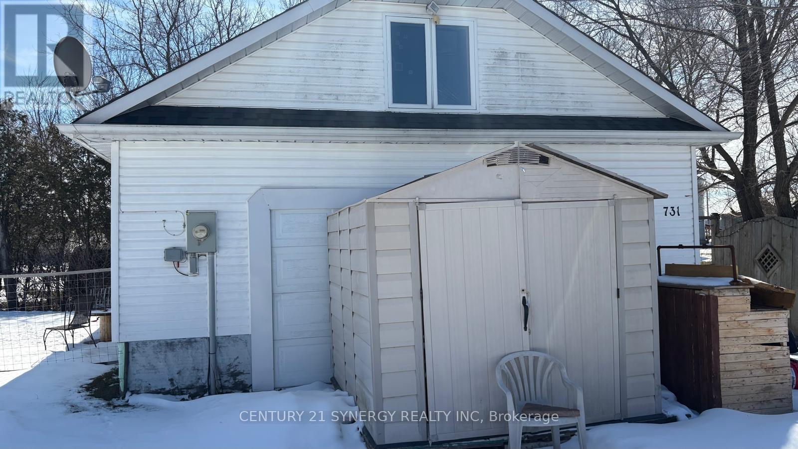 A white house with a shed in front of it.