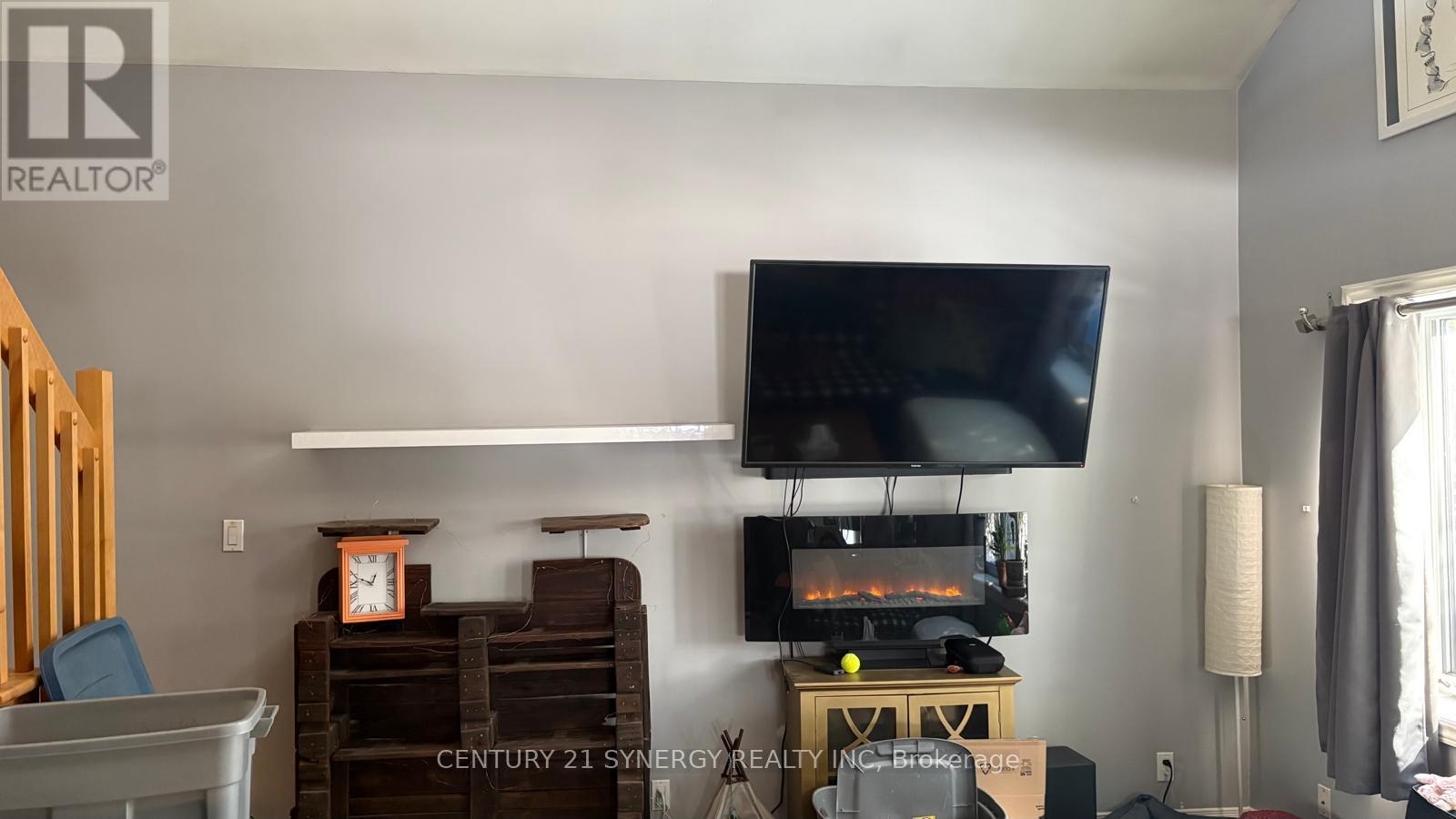 A living room with a television, a fireplace, and a chair.