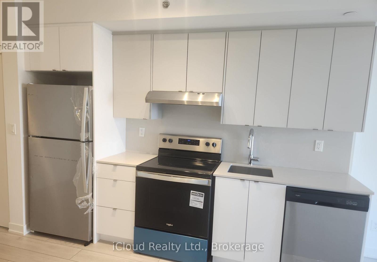 A kitchen with white cabinets and a stainless steel refrigerator.