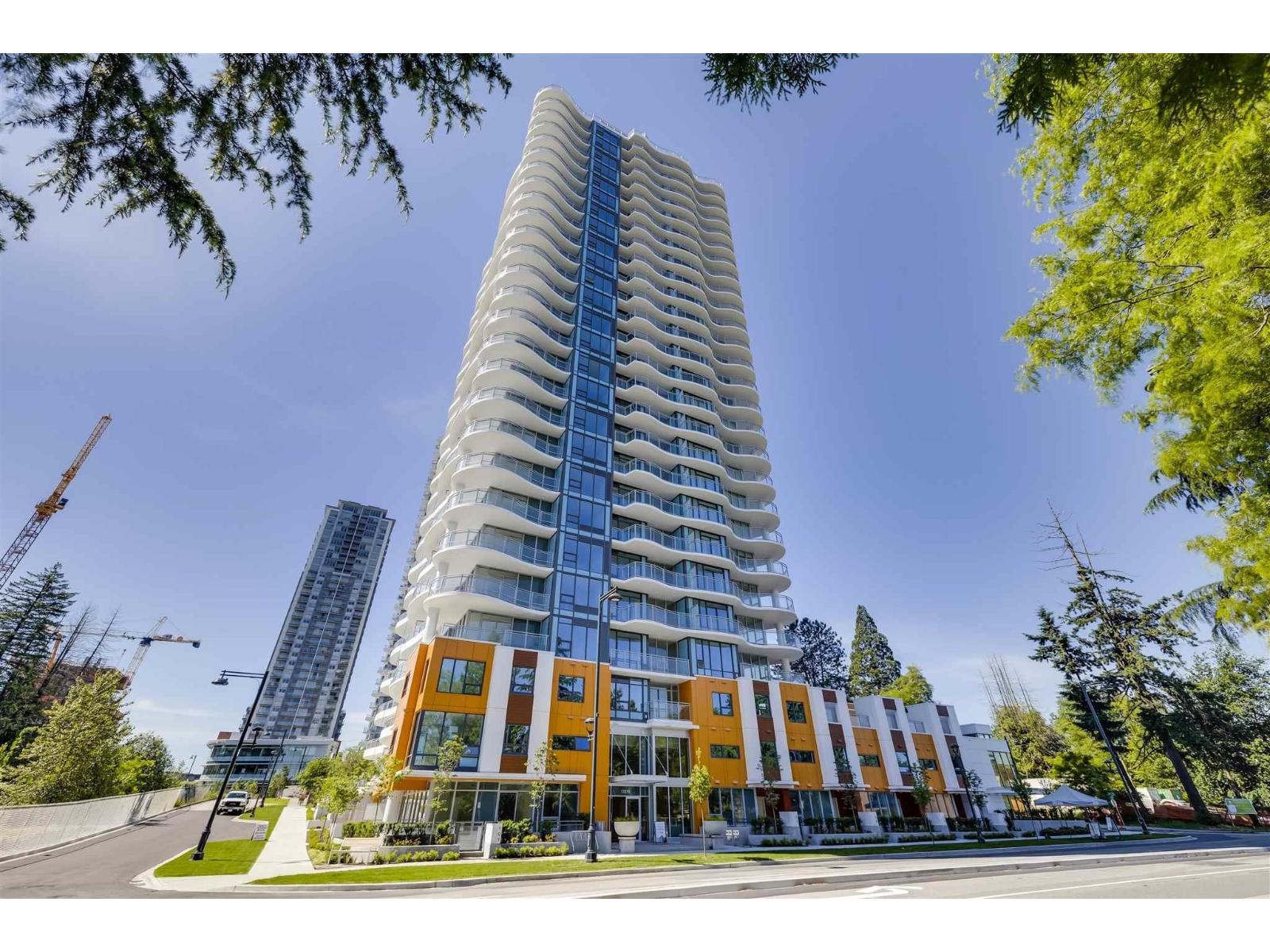 A tall, modern building with a curved design and orange and white balconies.