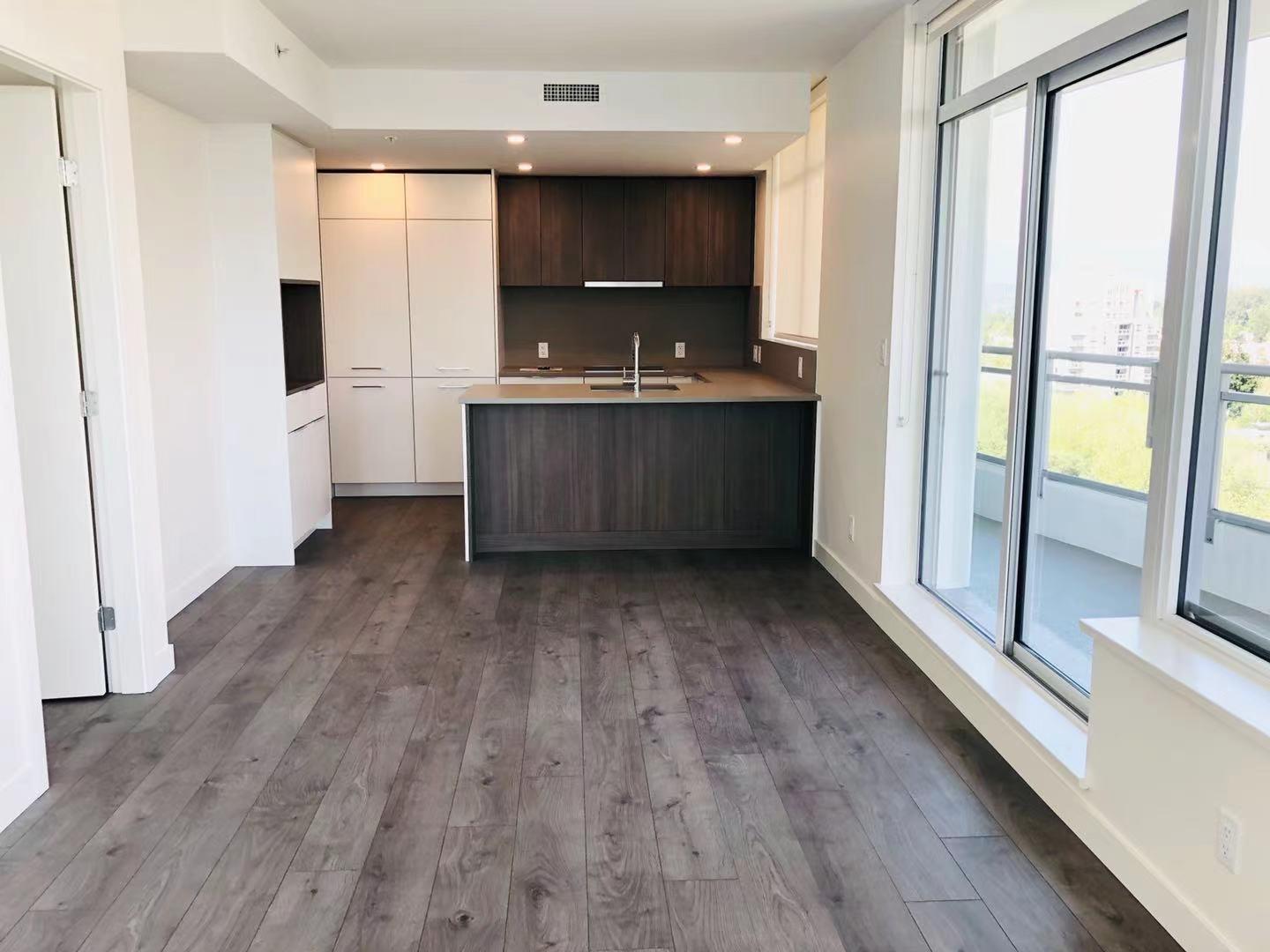 A kitchen with dark wood floors and white walls.