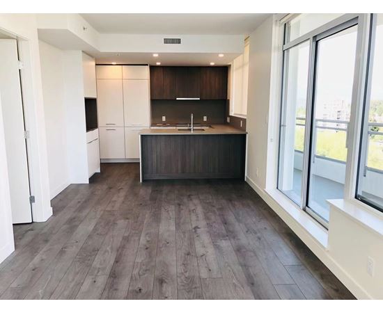 A kitchen with dark wood floors and white walls.