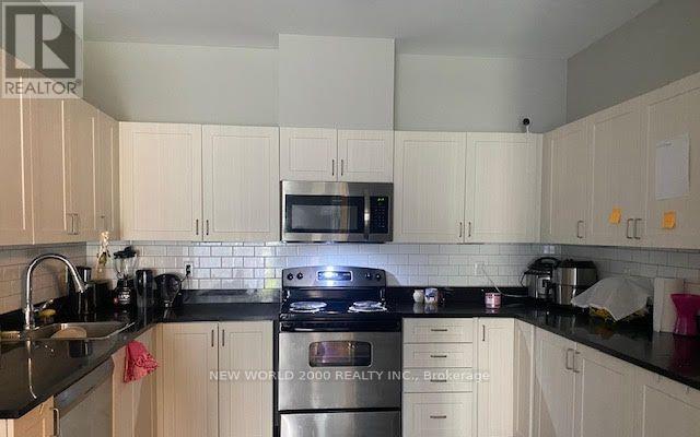 A kitchen with white cabinets and black countertops.