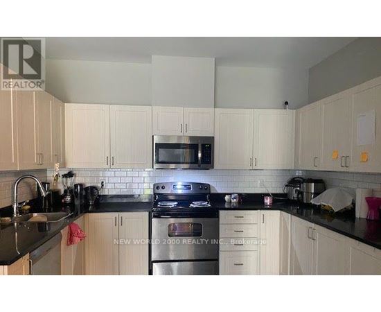 A kitchen with white cabinets and black countertops.