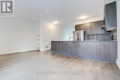 A kitchen with a stainless steel refrigerator and wooden flooring.