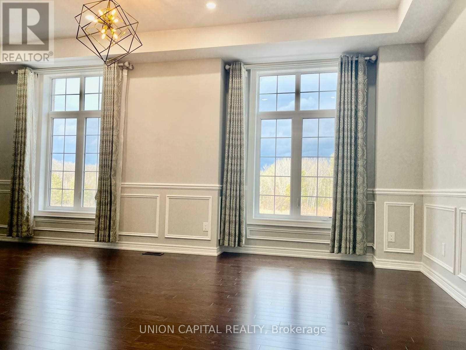 A room with wooden floors and a large window with curtains.