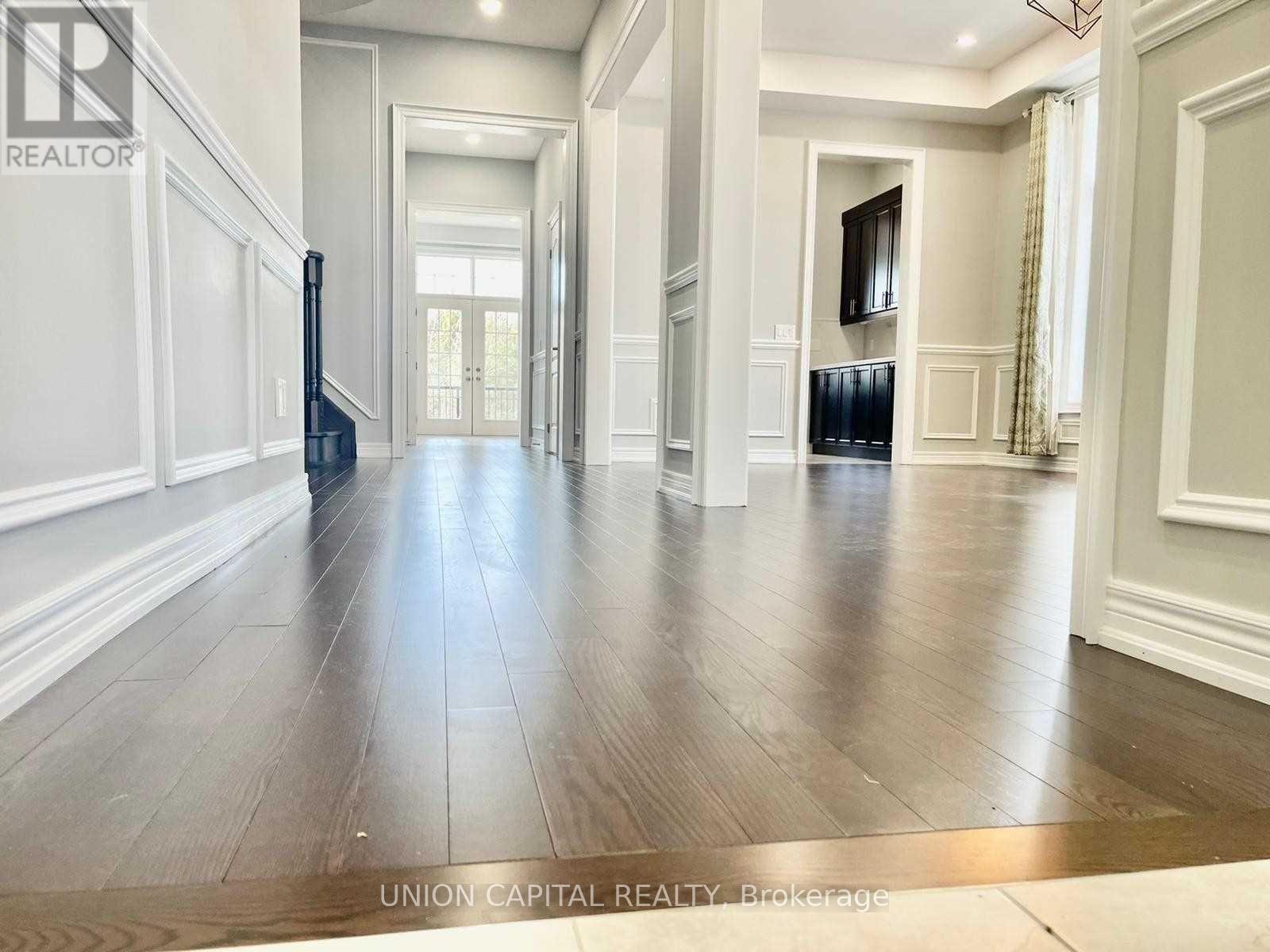 A spacious hallway with wood flooring and white walls.