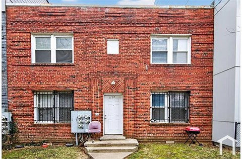 A red brick house with a white door and windows.
