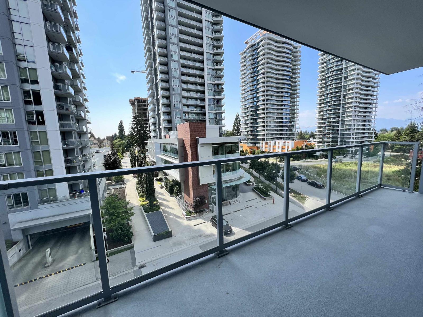 A balcony overlooks a parking lot and buildings.