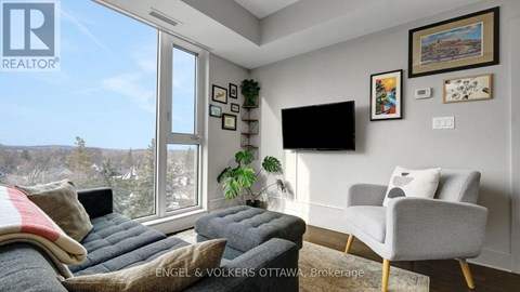 A living room with a grey couch and a flat screen TV mounted on the wall.