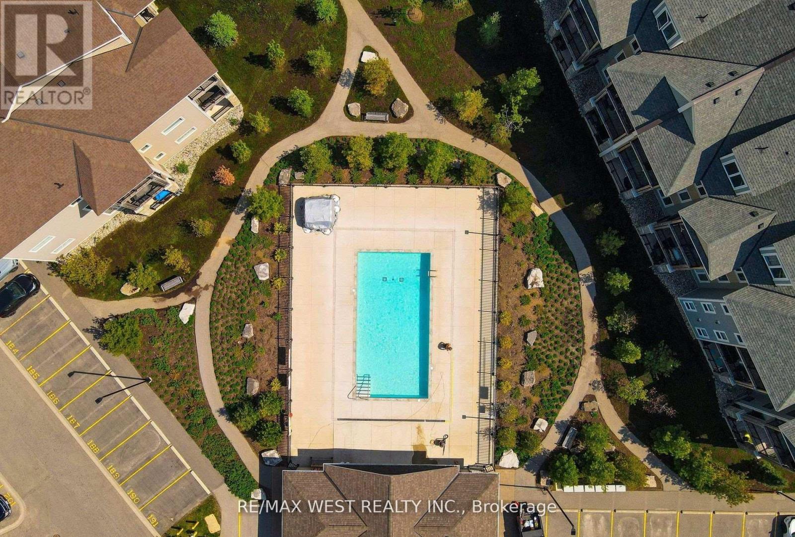A swimming pool surrounded by a grassy area and a parking lot.