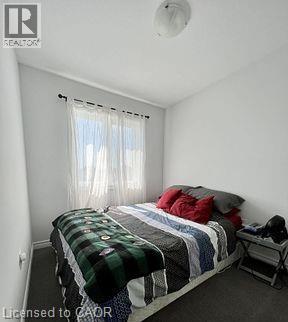 A bedroom with a bed covered in a plaid comforter and pillows.