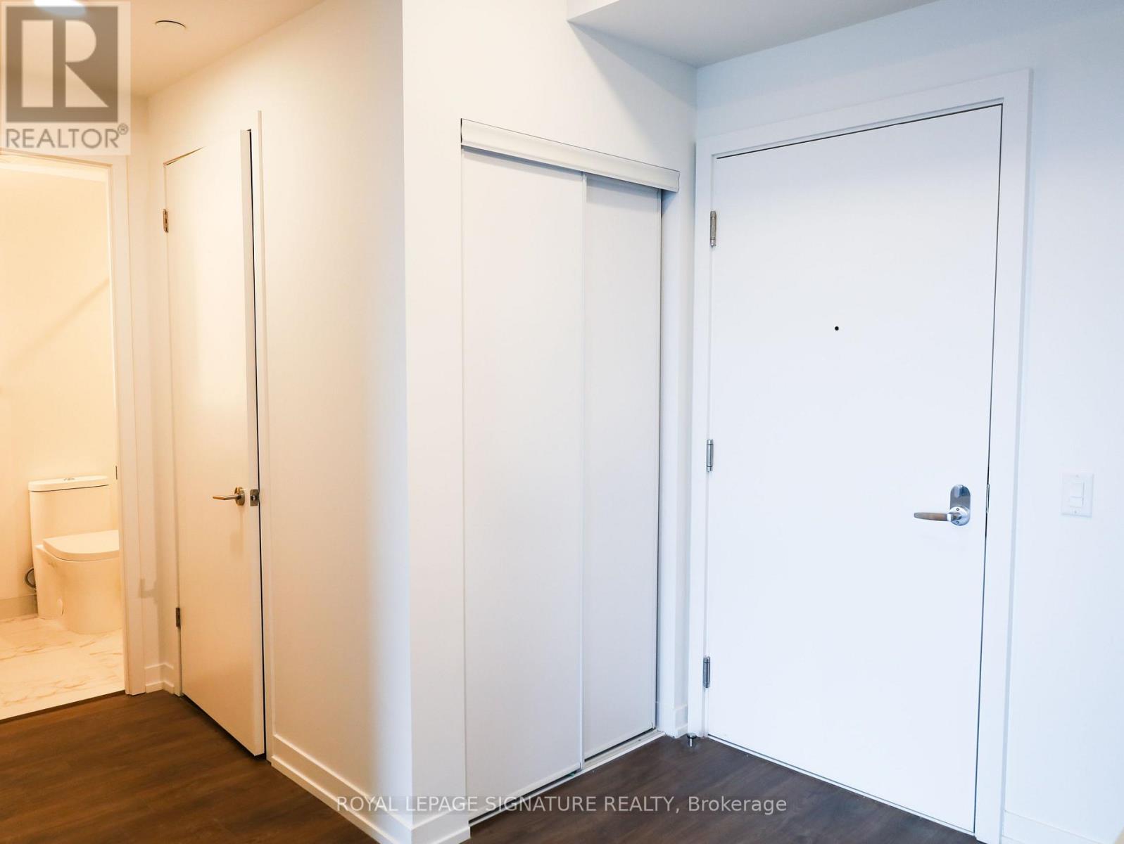 Three white doors in a hallway with a brokerage logo on the wall.