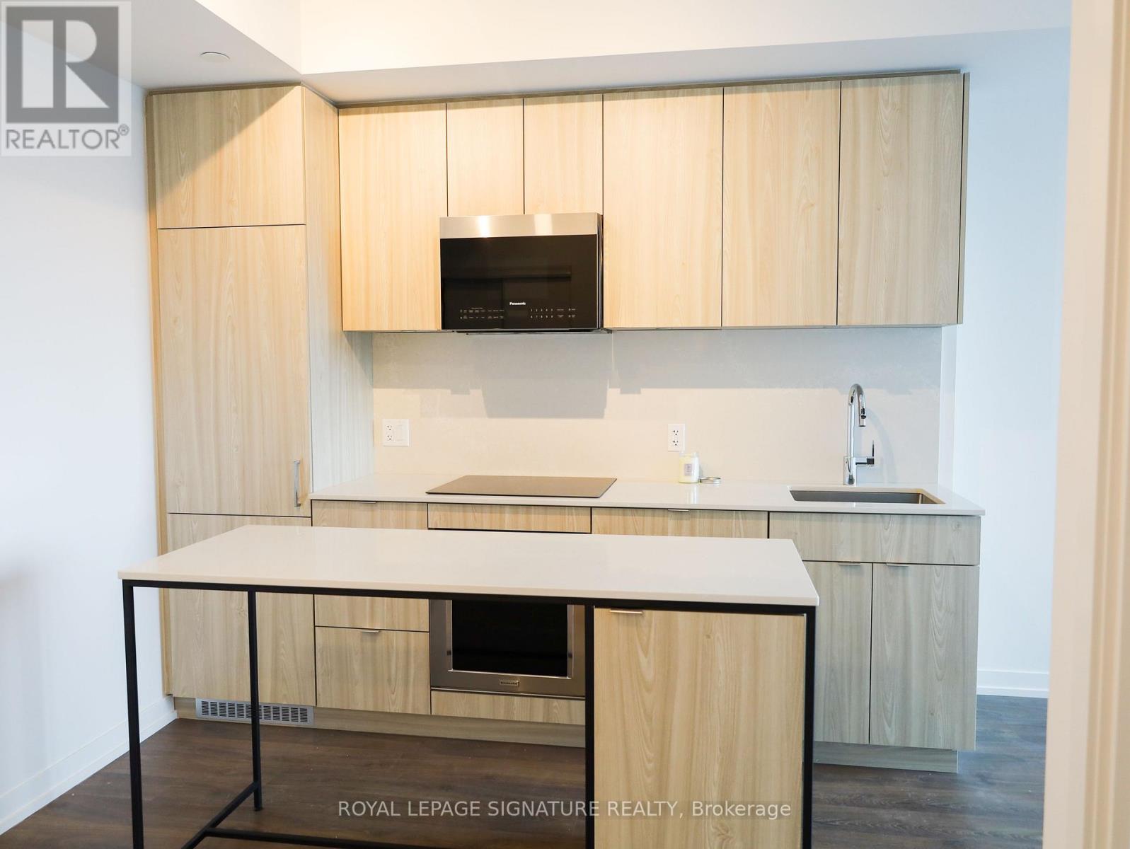 A kitchen with wooden cabinets and a black microwave above the stove.