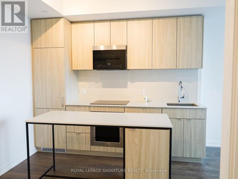 A kitchen with wooden cabinets and a black microwave above the stove.