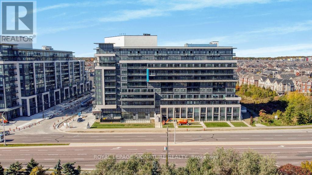 A large building with a glass facade is surrounded by trees and other buildings.