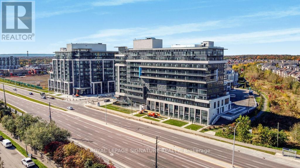 A large, modern building with a glass facade is situated on a road with multiple lanes.