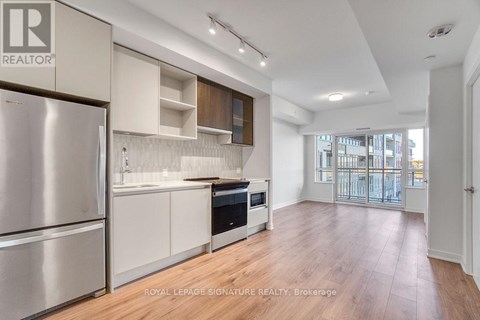 A kitchen with a refrigerator, microwave, oven and cabinets.