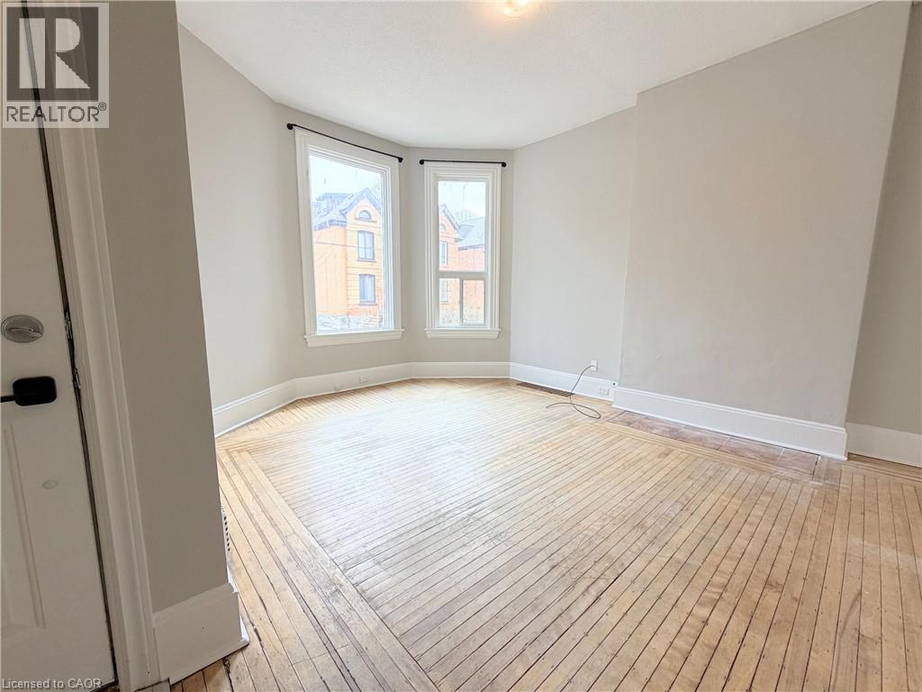 A room with wooden flooring and a window overlooking a building.