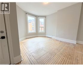 A room with wooden flooring and a window overlooking a building.
