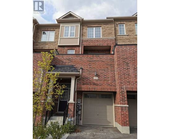 A brick house with a garage door and a tree in front.
