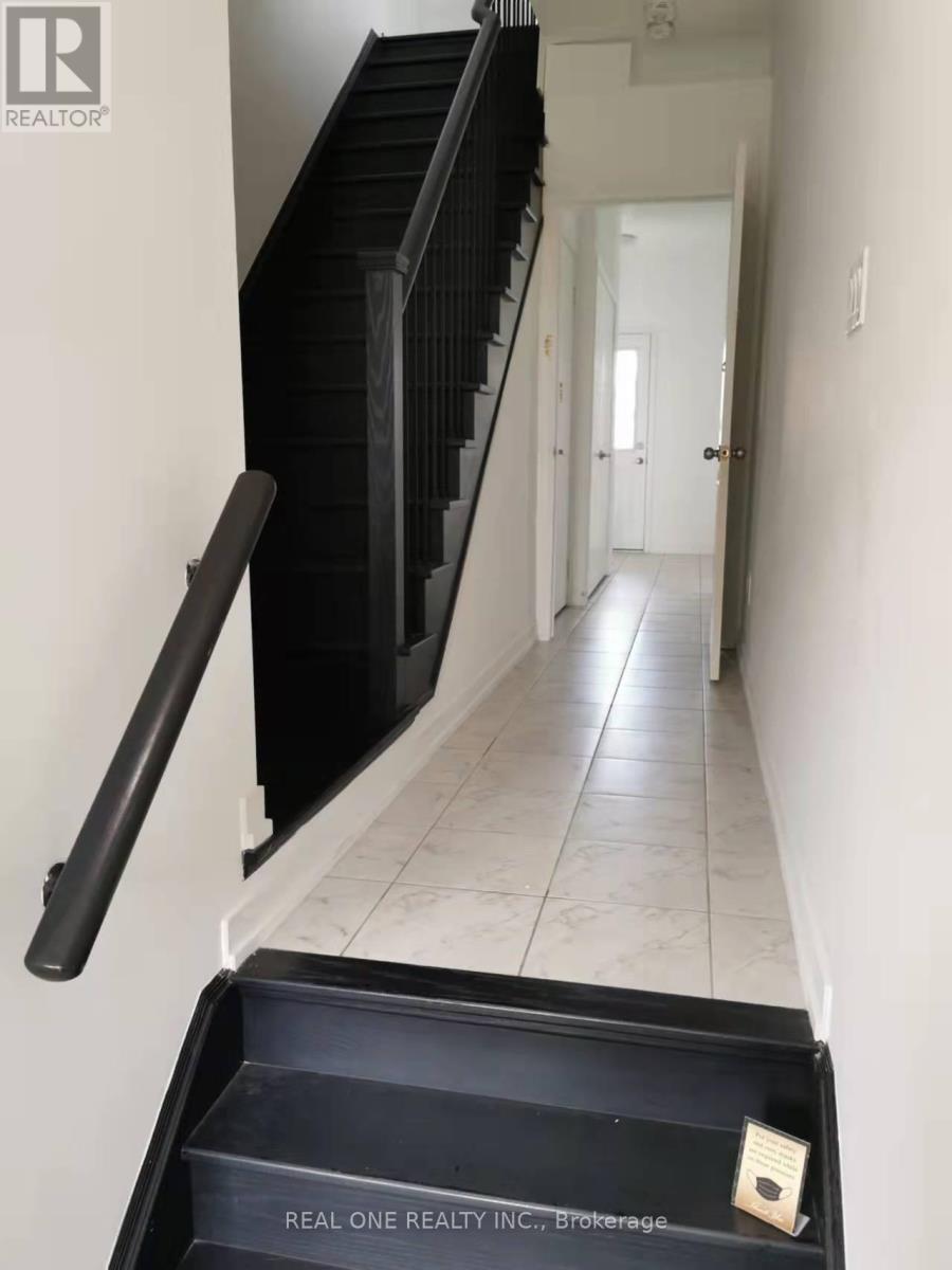 A hallway with a black railing and a sign that says Real One Realty Inc Brokerage.
