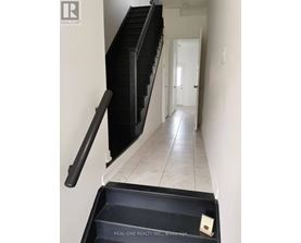 A hallway with a black railing and a sign that says Real One Realty Inc Brokerage.