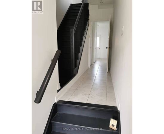 A hallway with a black railing and a sign that says Real One Realty Inc Brokerage.