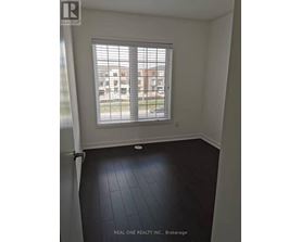 A room with a window and a view of a parking lot and buildings outside.